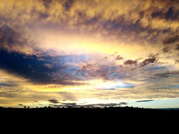 Silhouette landscape against dramatic sky during sunset
