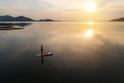Full length of man standing on paddleboard in lake