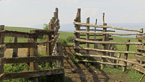 Old wooden fence on field against sky