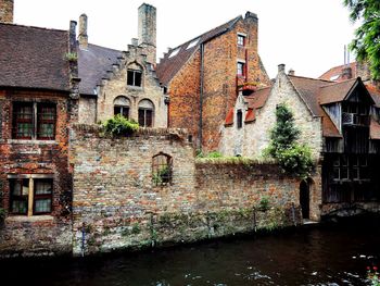 View of old building by canal against sky