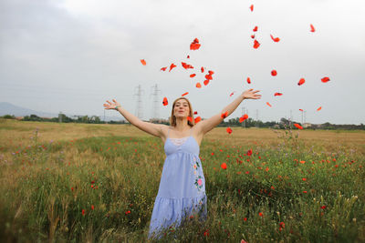 Woman with arms raised on field against sky