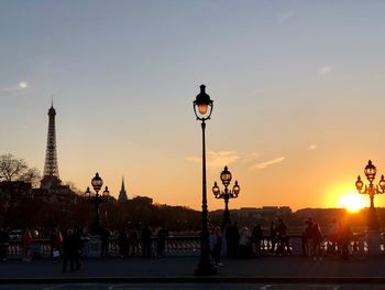 People on street against sky during sunset