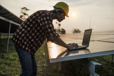 Side view of man using laptop while standing on table