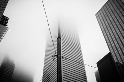 Low angle view of skyscrapers disappearing into fog