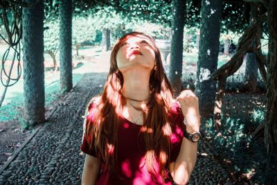 Young woman looking up while walking on footpath