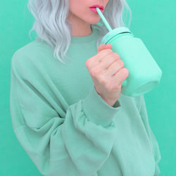 Midsection of woman holding drink jar against colored background