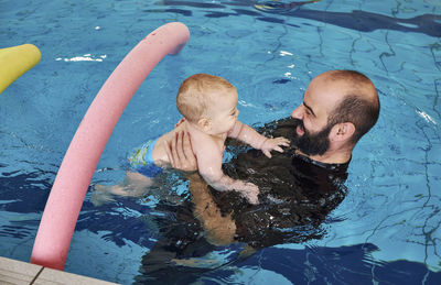 High angle view of boy and father swimming in pool