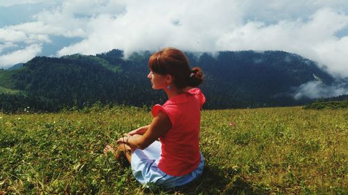 Woman on grassy field against cloudy sky