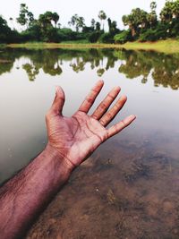 Reflection of person hand in lake