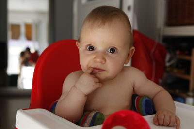 Close-up portrait of cute baby girl sitting on high chair