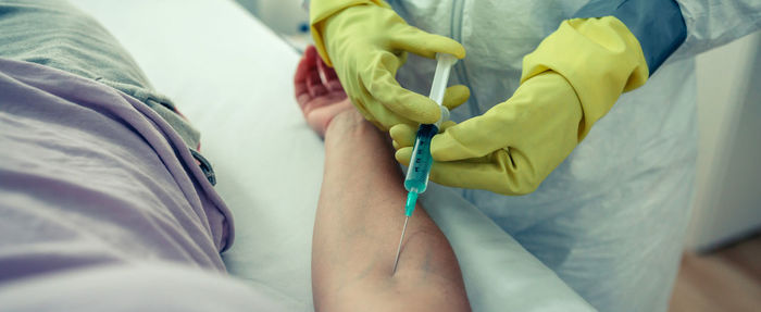 Midsection of doctor injecting patient in hospital