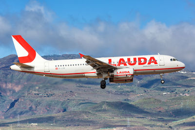 Airplane flying over mountain against sky