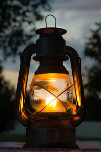 Close-up of illuminated lantern against sky at sunset