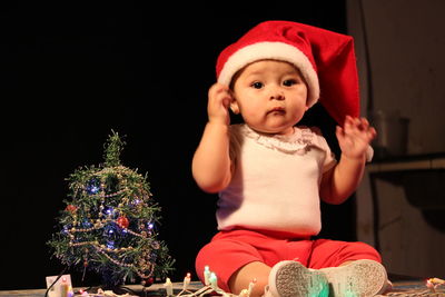 Cute baby wearing santa hat sitting at home