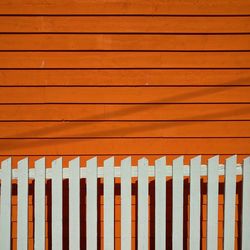 Full frame shot of wooden fence against orange wall