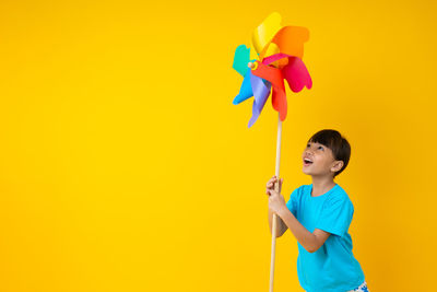 Boy holding toy against yellow background