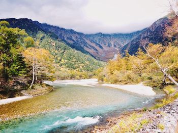 Scenic view of river amidst mountains against sky