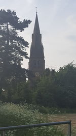 Church amidst trees and buildings against sky