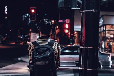 Rear view of man standing in city at night