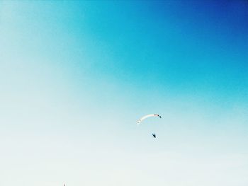 Low angle view of paragliding against clear blue sky