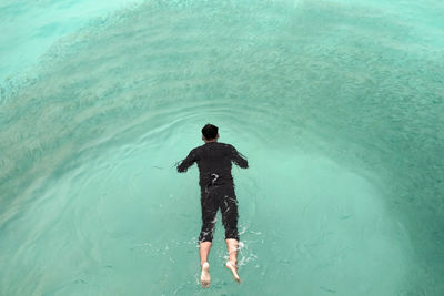 Rear view of shirtless man standing in swimming pool