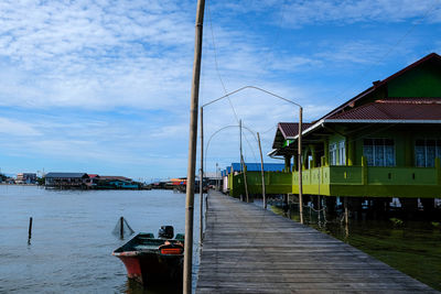 Sailboats in sea by buildings against sky