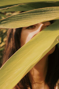 Close-up portrait of woman with green leaves