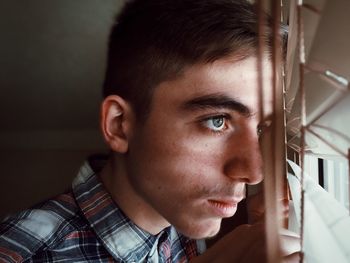 Close-up of thoughtful teenage boy looking through window
