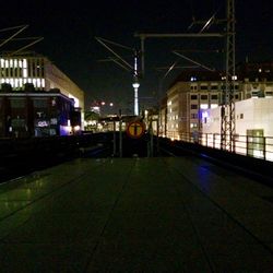 Illuminated railroad tracks by buildings in city at night