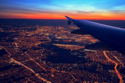 Aerial view of airplane over sea against sky during sunset