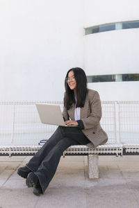 Smiling businesswoman with laptop sitting on bench