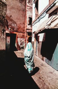 Rear view of man walking against building