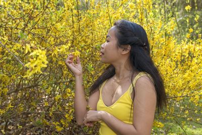 Young woman plucking flowers on tree