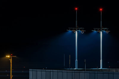 Low angle view of illuminated street lights against sky at night