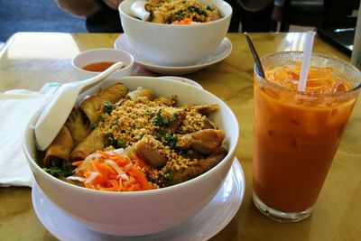 Close-up of spring rolls in bowl by drink on table