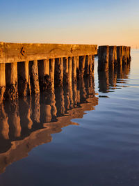 Wooden posts in sea against clear sky