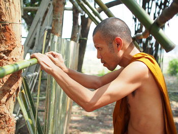 Side view of monk making bamboo fence