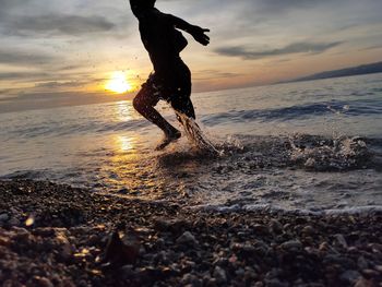 Low section of woman standing in water against sky