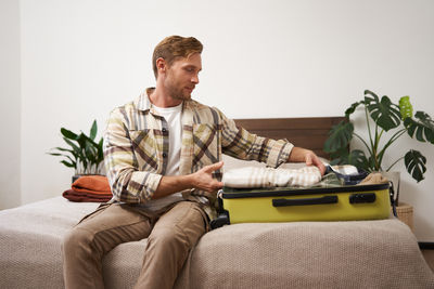 Senior man using mobile phone while sitting on sofa at home