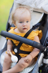 Portrait of cute caucasian baby girl in carriage in park 