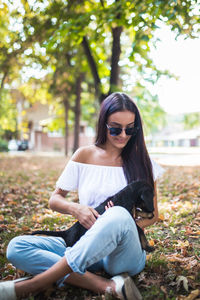 Young woman wearing sunglasses sitting on tree