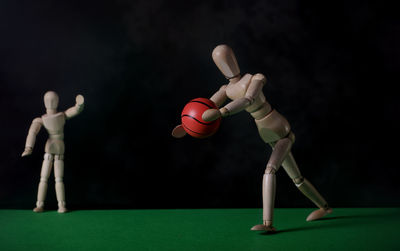 Wooden figurine with ball against black background