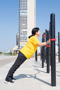 Side view of senior woman against sky in city