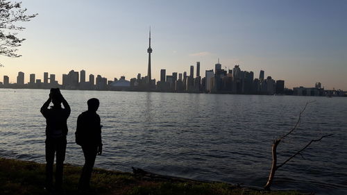 Silhouette of people standing by river in city