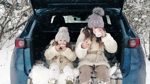 Winter tea picnic. happy cutie, dressed in warm winter clothes, are having tasty snack, tea party 