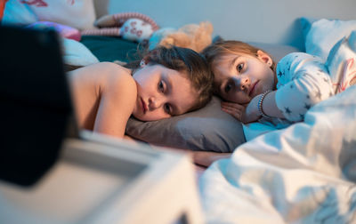 High angle view of siblings sleeping on bed at home