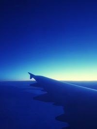 Airplane flying over sea against clear blue sky