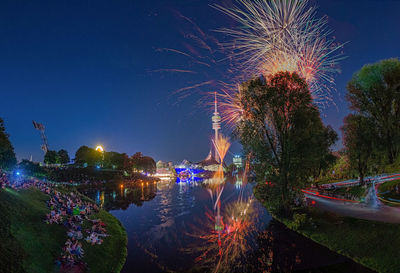 Firework display over lake against sky at night