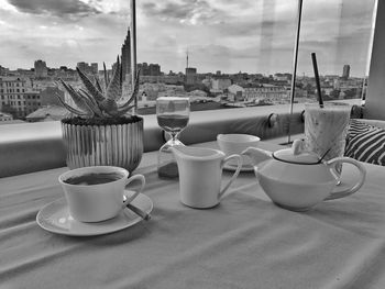 Coffee cup on table against sky in city