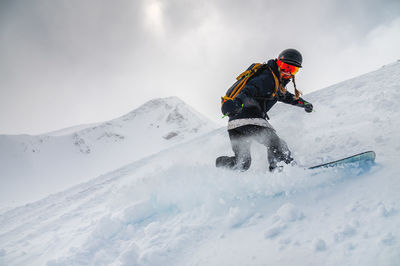 A young stylish girl is snowboarding on the powder against the backdrop of epic mountains. spa